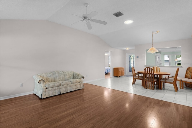 dining area with a ceiling fan, visible vents, baseboards, light wood finished floors, and lofted ceiling