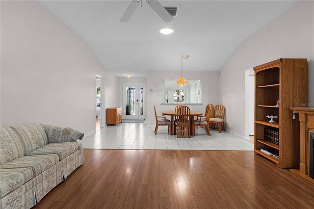 living room featuring a ceiling fan, baseboards, vaulted ceiling, and tile patterned flooring