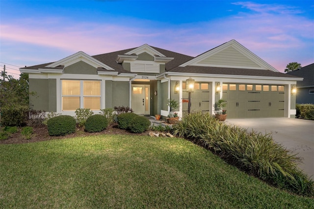 view of front of property featuring concrete driveway, a front yard, an attached garage, and stucco siding