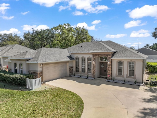 view of front of home with driveway, roof with shingles, an attached garage, a front lawn, and stucco siding