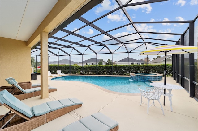 view of swimming pool featuring glass enclosure, a pool with connected hot tub, and a patio