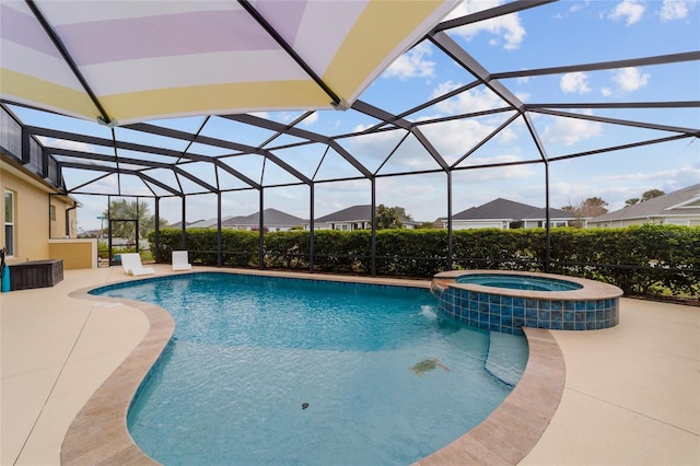 view of pool featuring glass enclosure, a pool with connected hot tub, and a patio area