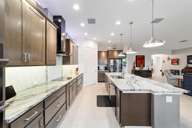 kitchen with visible vents, light tile patterned floors, arched walkways, wall chimney exhaust hood, and a sink