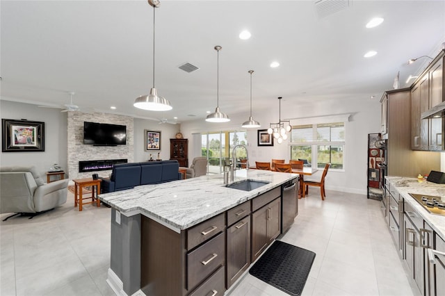 kitchen with visible vents, a fireplace, a sink, dishwasher, and open floor plan