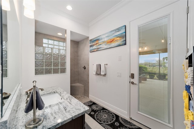 bathroom with crown molding, baseboards, a tile shower, recessed lighting, and vanity