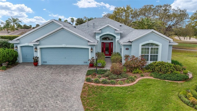 single story home with an attached garage, stucco siding, decorative driveway, and a front yard