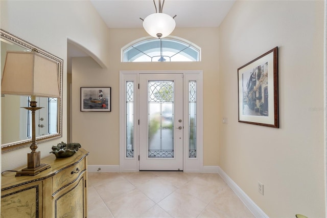 entrance foyer featuring light tile patterned floors, baseboards, and arched walkways