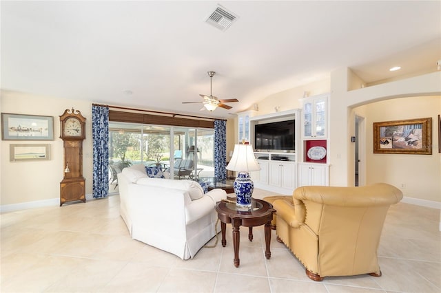 living area featuring lofted ceiling, visible vents, a ceiling fan, light tile patterned flooring, and baseboards