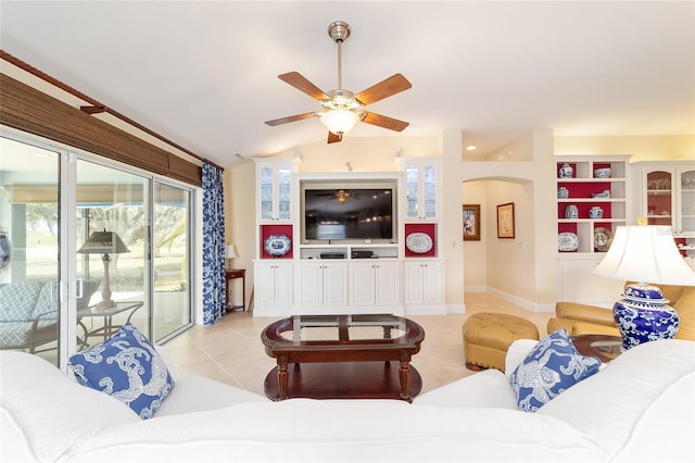 living area with light tile patterned floors, ceiling fan, arched walkways, baseboards, and vaulted ceiling