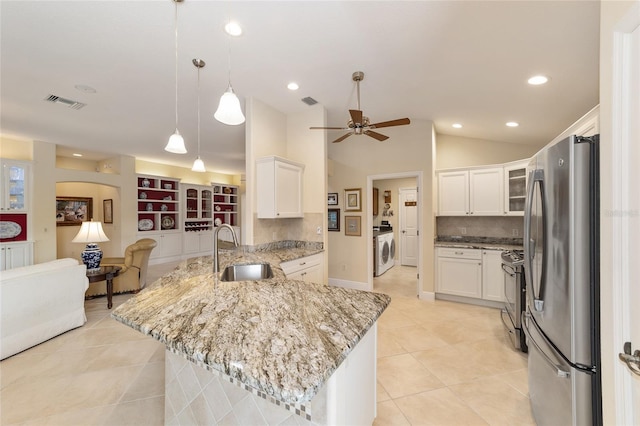 kitchen featuring white cabinets, washer / clothes dryer, a peninsula, stainless steel appliances, and a sink