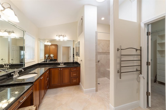 full bathroom featuring vaulted ceiling, double vanity, a sink, and a walk in shower