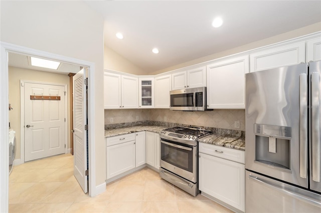 kitchen with stainless steel appliances, light stone countertops, white cabinets, and light tile patterned floors