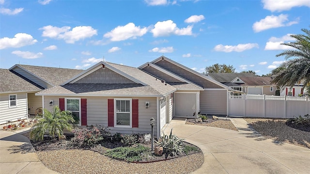 view of front of property featuring a garage, concrete driveway, a shingled roof, and fence