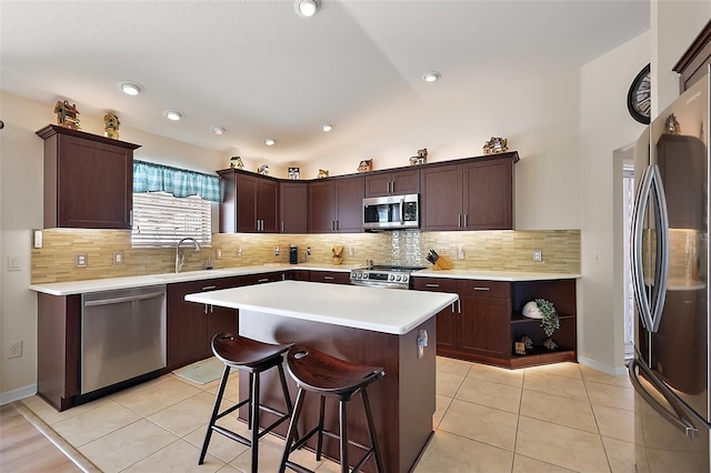 kitchen featuring stainless steel appliances, light tile patterned flooring, a sink, and a kitchen island