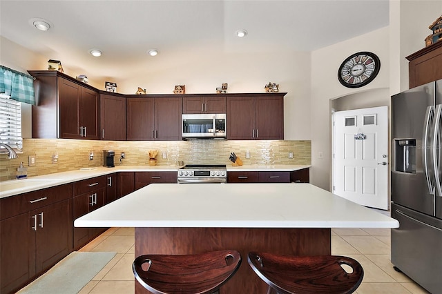 kitchen featuring light tile patterned floors, appliances with stainless steel finishes, a breakfast bar area, and a sink