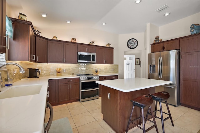 kitchen featuring lofted ceiling, visible vents, appliances with stainless steel finishes, a sink, and a kitchen island