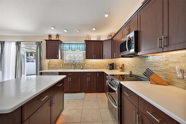 kitchen featuring light tile patterned floors, appliances with stainless steel finishes, a sink, light countertops, and backsplash