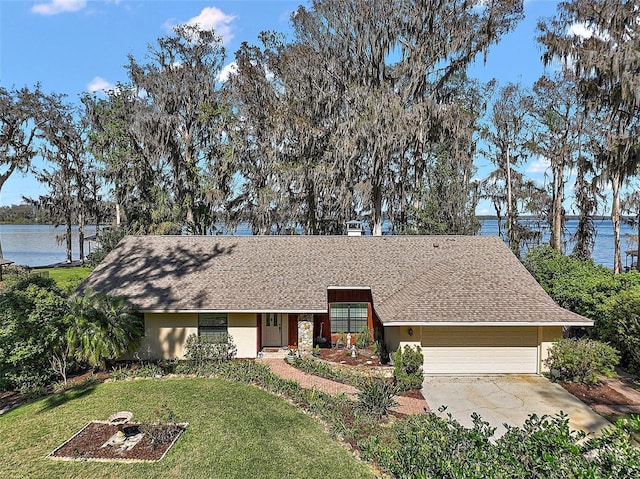 single story home featuring a garage, concrete driveway, stucco siding, a water view, and a front yard