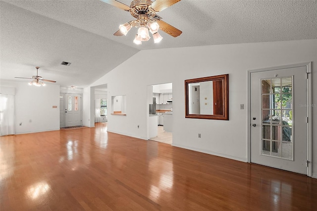 unfurnished living room featuring vaulted ceiling, light wood-style flooring, and a healthy amount of sunlight