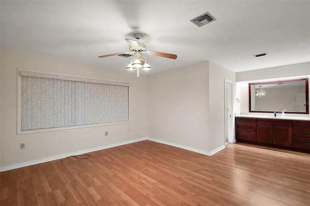 unfurnished room featuring light wood-type flooring, baseboards, visible vents, and a ceiling fan