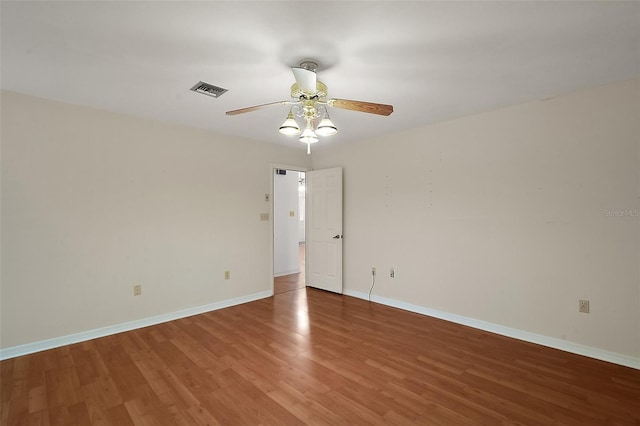 empty room featuring a ceiling fan, baseboards, visible vents, and wood finished floors