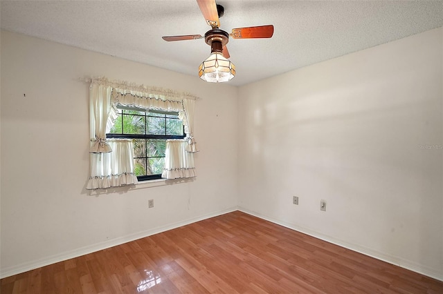 unfurnished room with a ceiling fan, a textured ceiling, baseboards, and wood finished floors