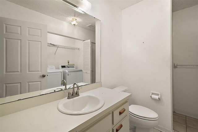 bathroom featuring toilet, vanity, a textured ceiling, washer and dryer, and tile patterned floors