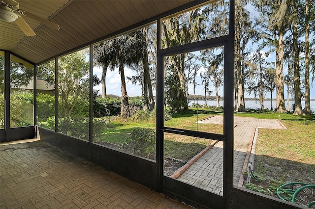 unfurnished sunroom featuring a water view, plenty of natural light, and ceiling fan