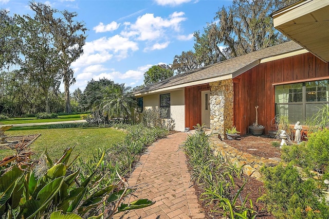 property entrance with stone siding and a lawn