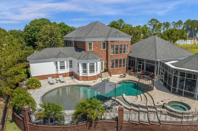 back of property with a fenced in pool, glass enclosure, a patio area, an in ground hot tub, and a fenced backyard