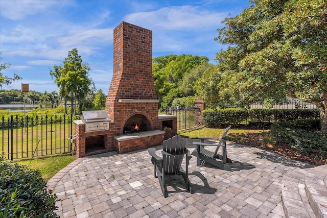 view of patio with an outdoor brick fireplace, fence, and a grill