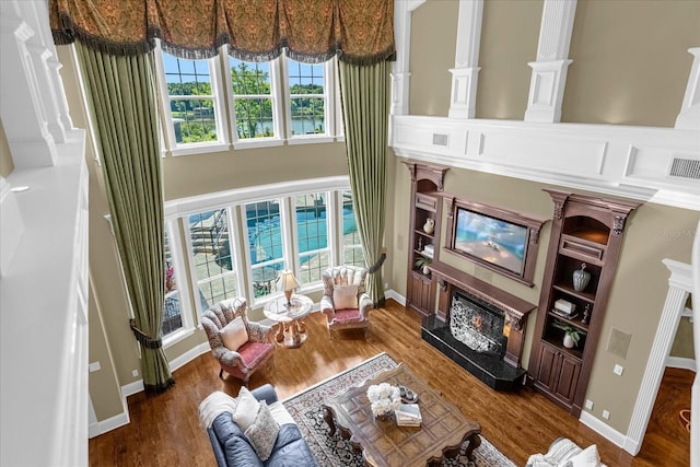 living room featuring a fireplace, wood finished floors, visible vents, and baseboards