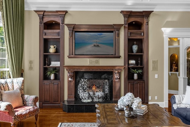 living room with built in features, a fireplace, ornamental molding, wood finished floors, and baseboards