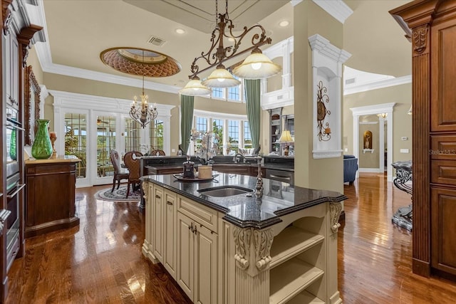 kitchen featuring cream cabinets, crown molding, stainless steel oven, and dark stone countertops