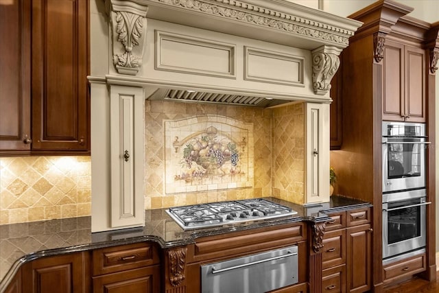 kitchen featuring stainless steel appliances, dark stone counters, a warming drawer, and backsplash