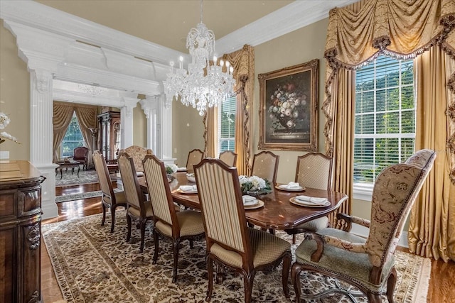 dining area with ornamental molding, wood finished floors, decorative columns, and an inviting chandelier