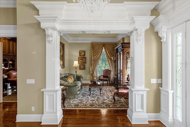 living area with baseboards, crown molding, ornate columns, and wood finished floors