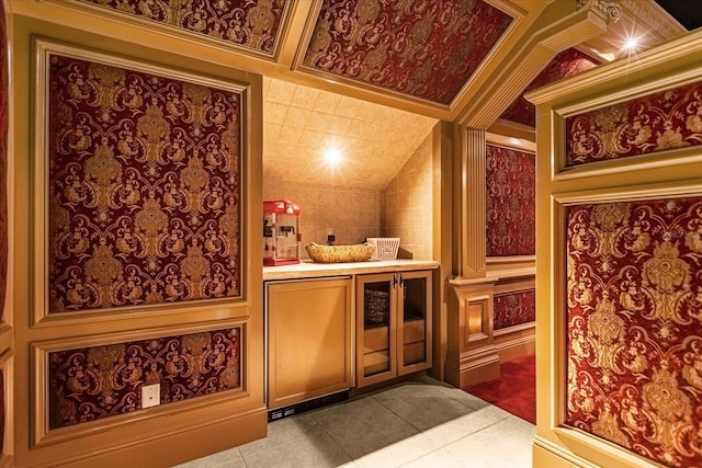 bar with lofted ceiling, ornamental molding, and tile patterned flooring