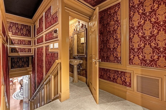 interior space with light tile patterned floors, crown molding, and an upstairs landing