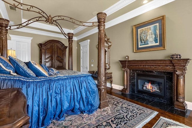 bedroom featuring baseboards, visible vents, a premium fireplace, ornamental molding, and wood finished floors