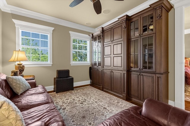 living area with a ceiling fan, crown molding, baseboards, and wood finished floors