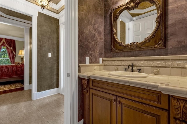 bathroom with ensuite bathroom, ornamental molding, vanity, baseboards, and wallpapered walls