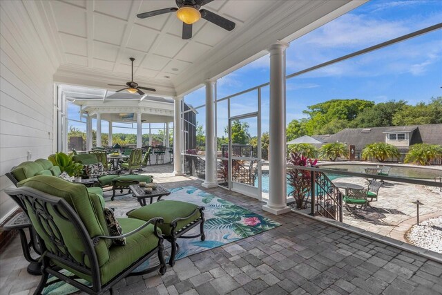 sunroom featuring coffered ceiling, decorative columns, and ceiling fan