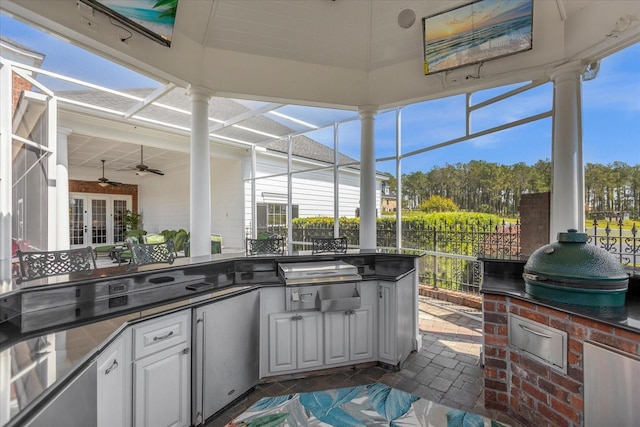 view of patio with a lanai, a grill, a ceiling fan, french doors, and exterior kitchen