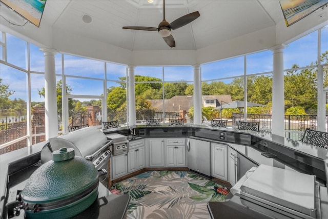 sunroom featuring a ceiling fan, vaulted ceiling, plenty of natural light, and ornate columns