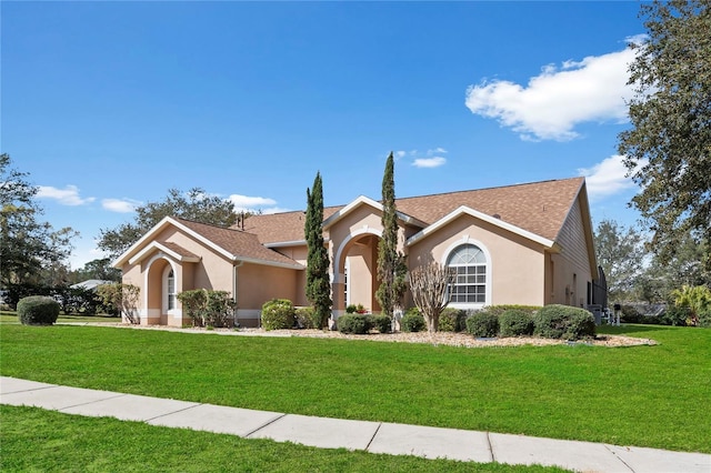 view of front facade featuring a shingled roof, a front yard, and stucco siding