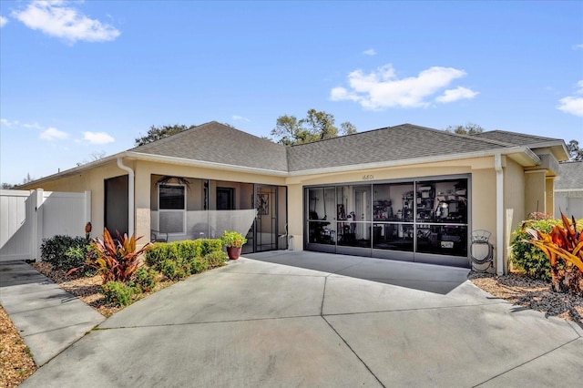 ranch-style home with roof with shingles, stucco siding, concrete driveway, fence, and a garage