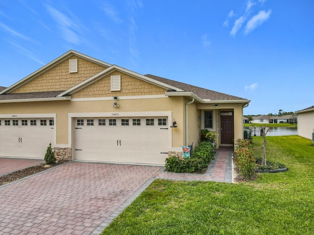 view of front of property featuring stucco siding, roof with shingles, an attached garage, decorative driveway, and a front yard