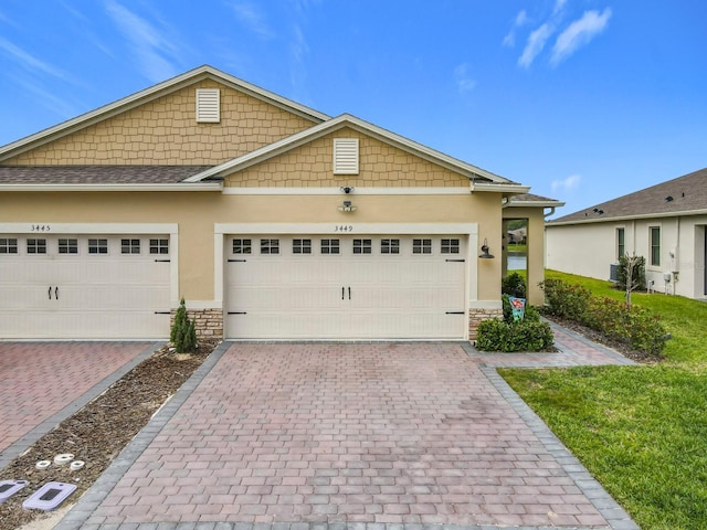 view of front of house with stone siding, decorative driveway, an attached garage, and stucco siding