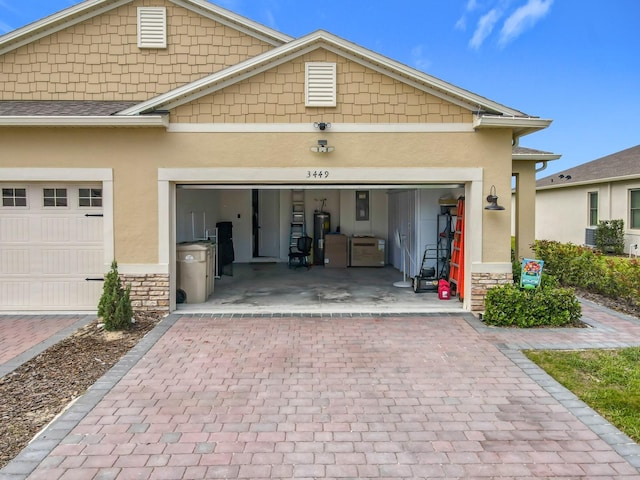 view of front facade featuring stone siding, decorative driveway, electric water heater, and stucco siding